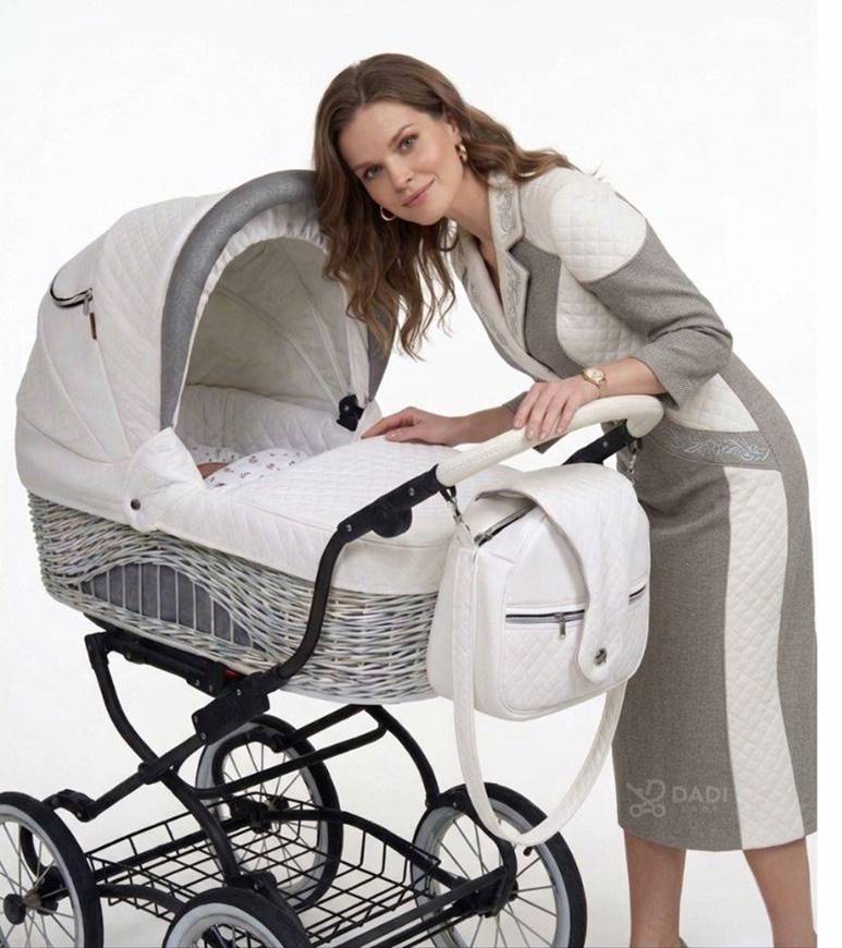 Stylowy wózek dziecięcy Baby Fashion Scarlett z wiklinową gondolą i nowoczesnym stelażem, prezentowany przez kobietę.